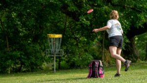 female playing disc golf in the summer